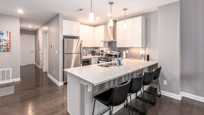 A modern kitchen with stainless steel appliances, a large island with bar stools, and pendant lighting. - Soaring 2-Bedroom Parkside Loft Walkable to it All (Cincinnati)