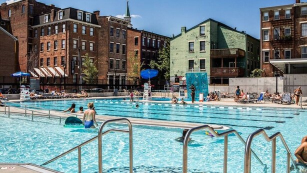 A public swimming pool with multiple lanes, surrounded by multi-story buildings with brick facades. - Deluxe 5-bedroom Condo Walkable to Everything (Cincinnati)