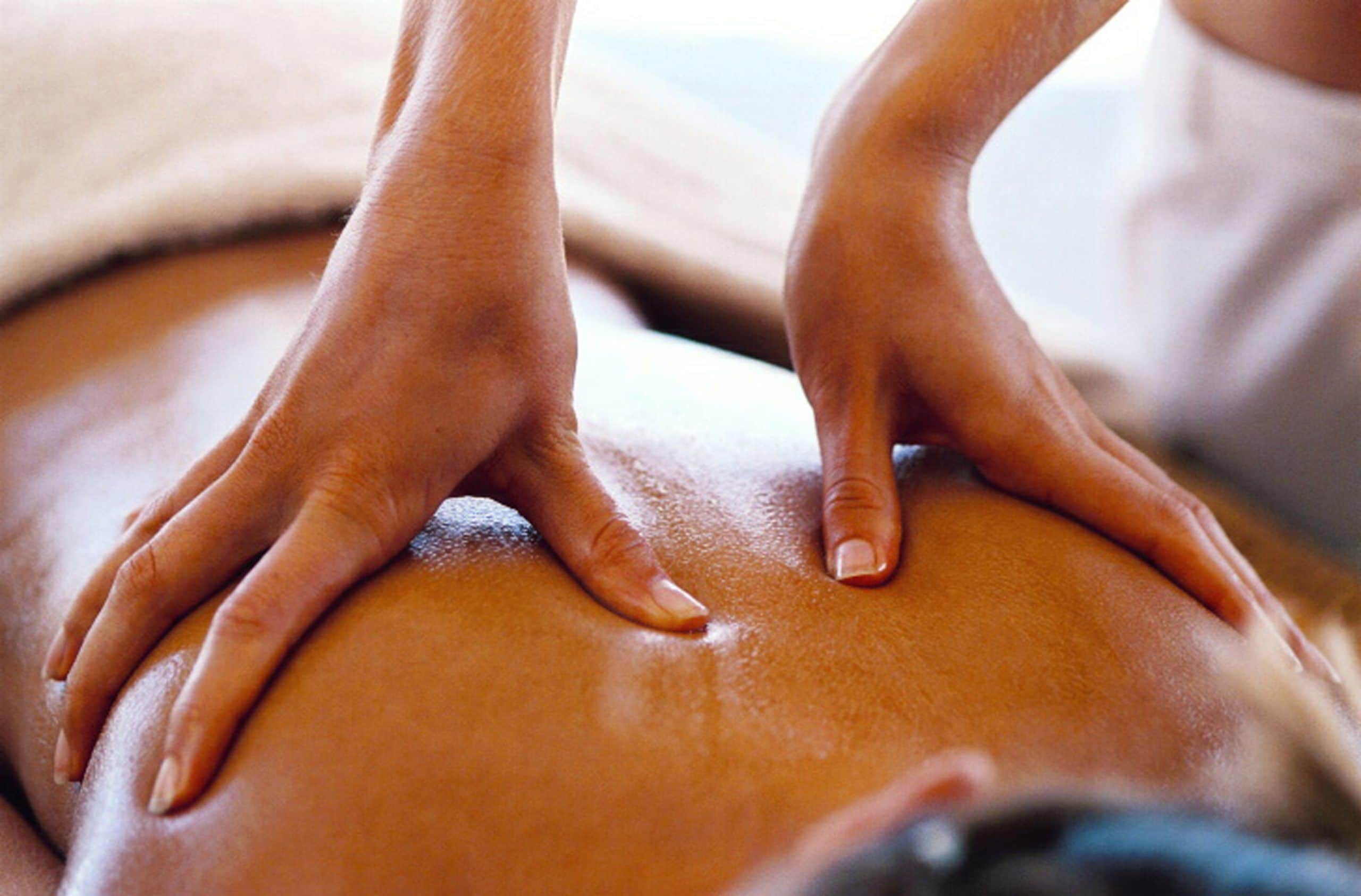 Hands performing a massage on a person's back.