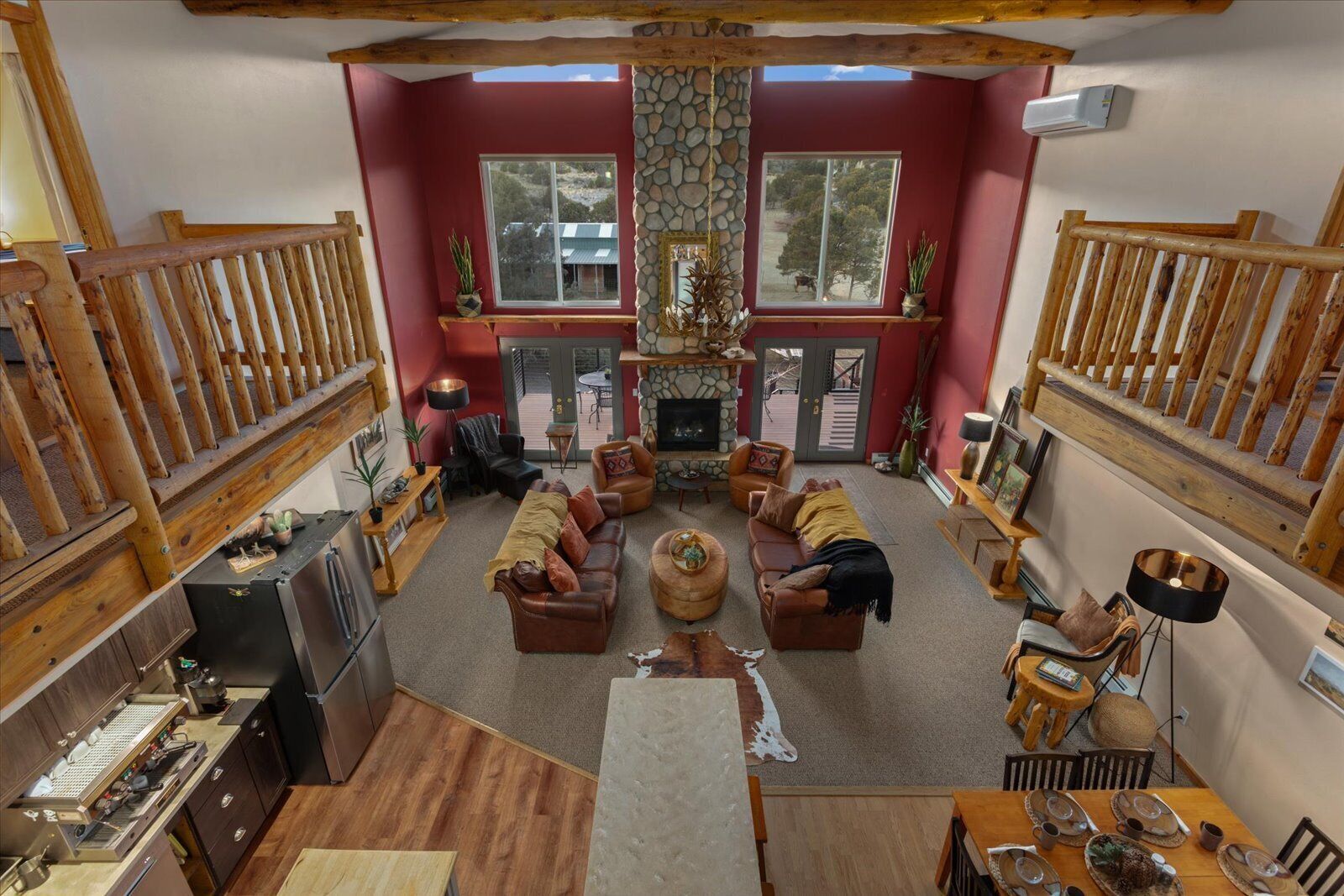 A spacious living room with a fireplace, wooden furniture, and large windows.
