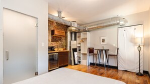 Une chambre d’hôtel compacte dotée d’une kitchenette, d’un coin repas et d’un grand lit.