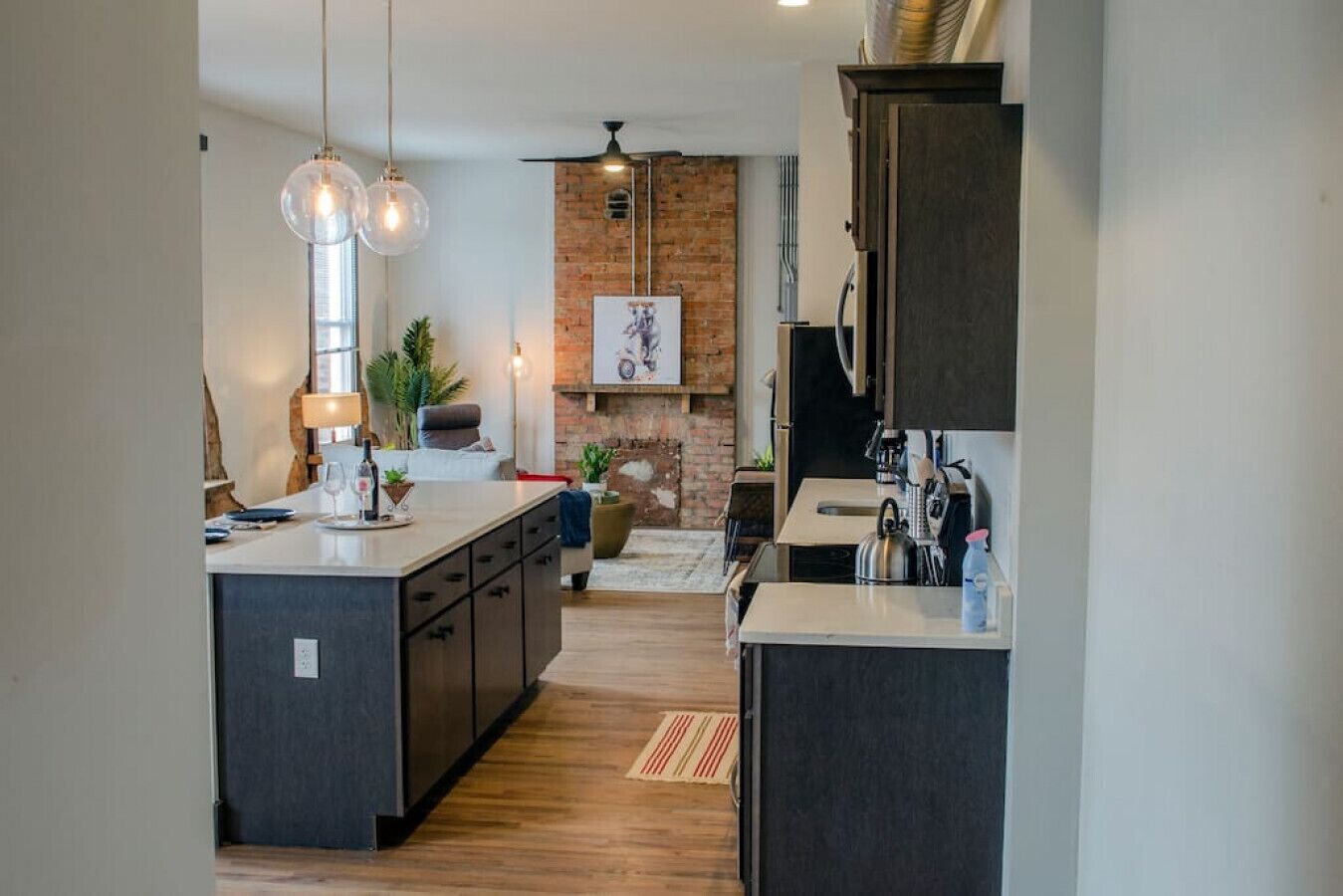 A modern kitchen with a central island, dark cabinetry, and pendant lighting.