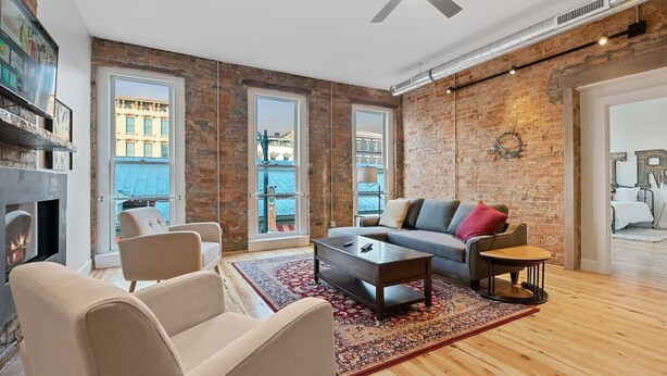 Una sala de estar moderna con chimenea, ventanas amplias y un ventilador de techo.