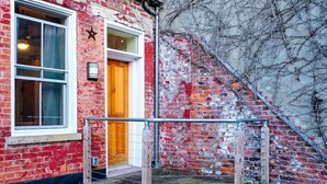 A red brick building with a wooden door and a star-shaped sign on the wall. - Cozy OTR Home with Private Roof Deck (Cincinnati)