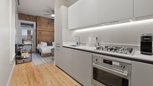A modern kitchen with white cabinets, a built-in oven, and a coffee machine. - Over the Rhine Luxury MicroSuite On Findlay Market (Cincinnati)