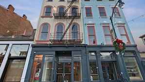 A multi-story building with a fire escape, large windows, and a storefront with a visible sign. - Over the Rhine Luxury MicroSuite On Findlay Market (Cincinnati)