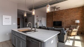 A modern kitchen with a central island, grey cabinetry, and pendant lighting.