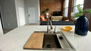 A modern kitchen with a central island, stainless steel sink, and a ceiling fan.