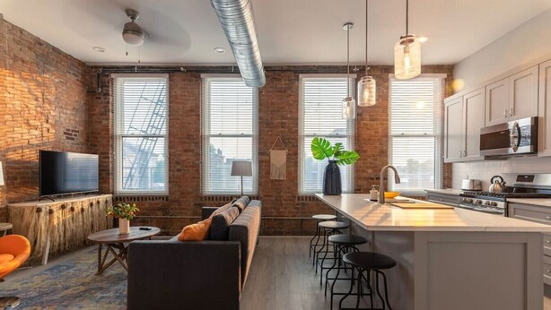 A modern kitchen with a central island, bar stools, and a built-in oven.