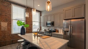 A modern kitchen with a large island, stainless steel appliances, and pendant lighting.