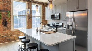 Una cocina moderna con una isla grande, electrodomésticos de acero inoxidable y una pared de ladrillo.