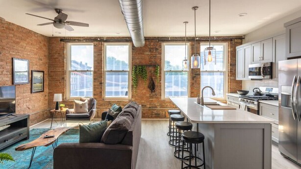Una cocina moderna con una isla central, electrodomésticos de acero inoxidable y grandes ventanales.