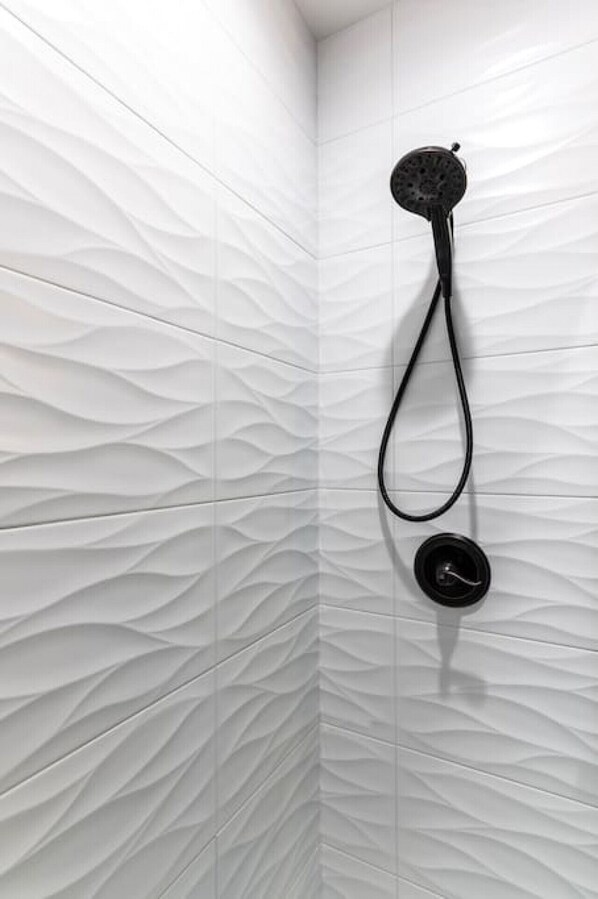 A shower with a textured wall and a modern faucet.