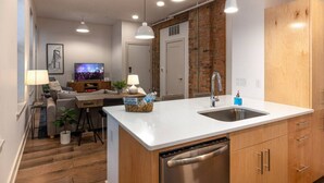 Une cuisine moderne dotée d’un îlot central, d’appareils électroménagers en acier inoxydable, de meubles en bois et de luminaires suspendus.