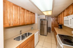 Una cocina con armarios de madera, electrodomésticos de acero inoxidable, un lavamanos doble y una estufa a gas.