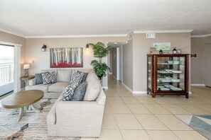 A living room with a sofa, coffee table, and a glass display cabinet. - Ocean House 322 Ocean Vistas (St. Augustine)