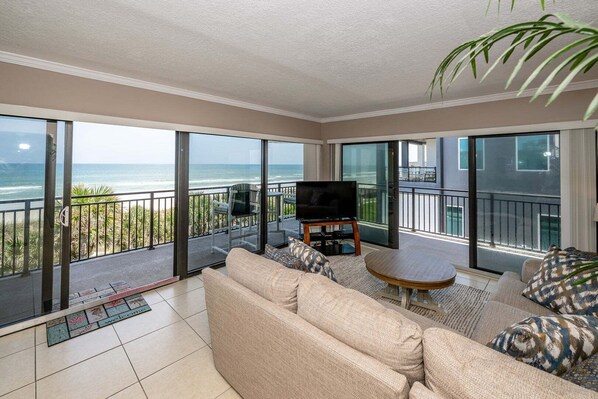 Ein geräumiger Balkon mit einer Couch, einem kleinen Tisch und einem Fernseher.