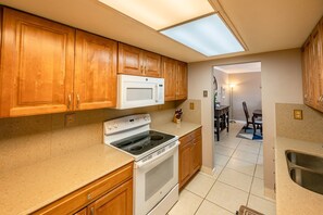 A kitchen with wooden cabinets, a white stove, a microwave, and a skylight.