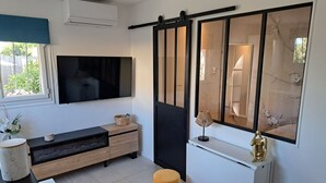 Una sala de estar moderna con televisor, un espejo grande, un sofá y una mesita con adornos.