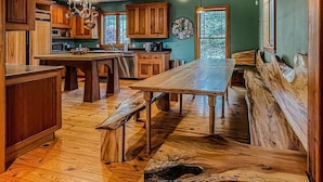 A spacious kitchen with wooden cabinets, a large island, and a rustic wooden bench.