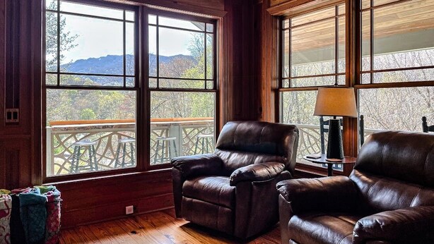 A room with large windows, a wooden ceiling, and leather chairs.