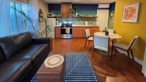 A compact living space with a sofa, dining table, chairs, and a kitchenette. - Angeleno Oasis: Cute Guest House w/ Private Patio (YUC)