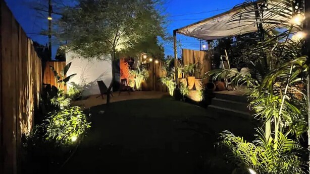 A covered outdoor area with a wooden fence, potted plants, and a seating area. - Angeleno Oasis: Cute Guest House w/ Private Patio (YUC)