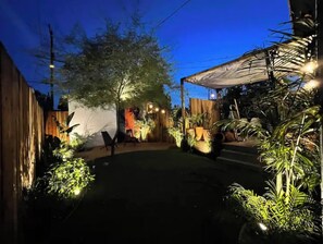 A covered outdoor area with a wooden fence, potted plants, and a seating area. - Angeleno Oasis: Cute Guest House w/ Private Patio (YUC)