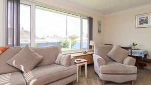 Ein Wohnzimmer mit einer Couch, einem Sessel und einem kleinen Tisch mit einer Lampe.