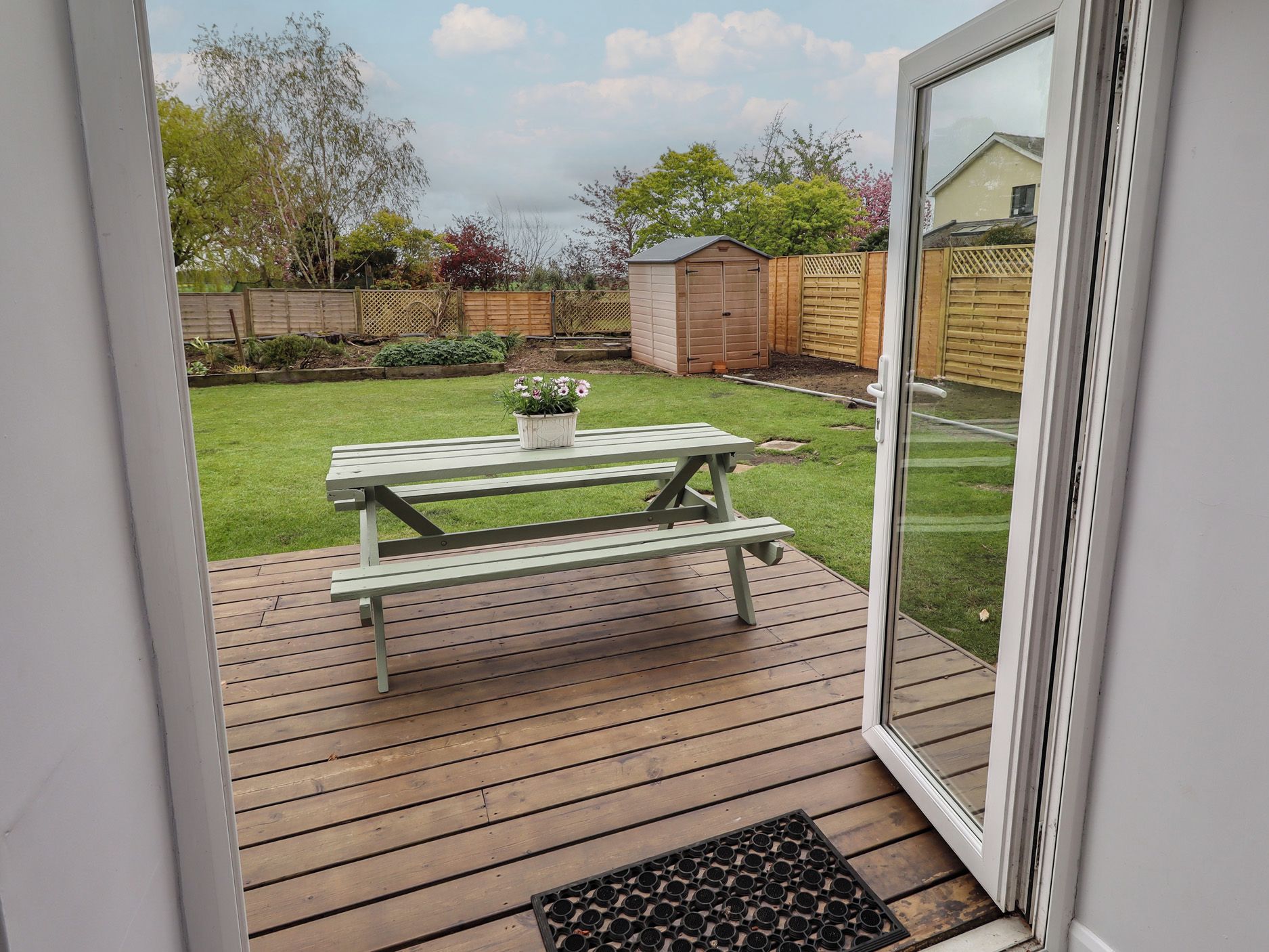 A wooden deck with a picnic table and a potted plant.