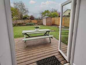 A wooden deck with a picnic table and a potted plant.