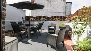 A patio with outdoor furniture, a table, and a large umbrella. - Westfield (Bridlington)