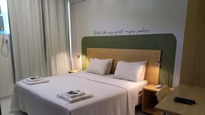 Una habitación de hotel con una cama, una mesita de noche, una silla y un escritorio con un teclado.