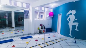 Un gimnasio con equipo de ejercicio, una pared azul con una silueta y una ventana que ofrece vistas al exterior.
