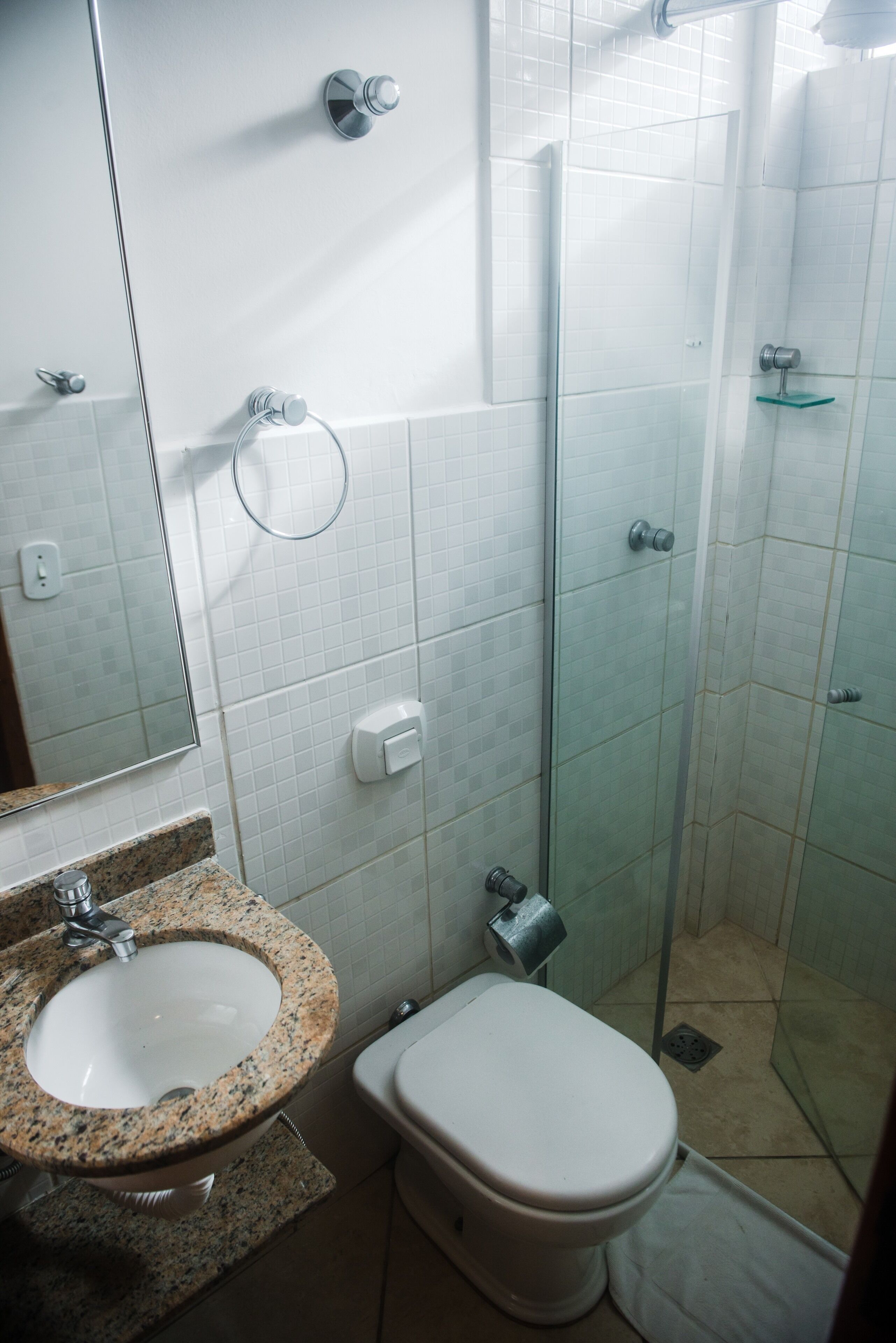 Ein Badezimmer mit einem Marmorwaschbecken, einer weißen Toilette und einer Duschkabine.