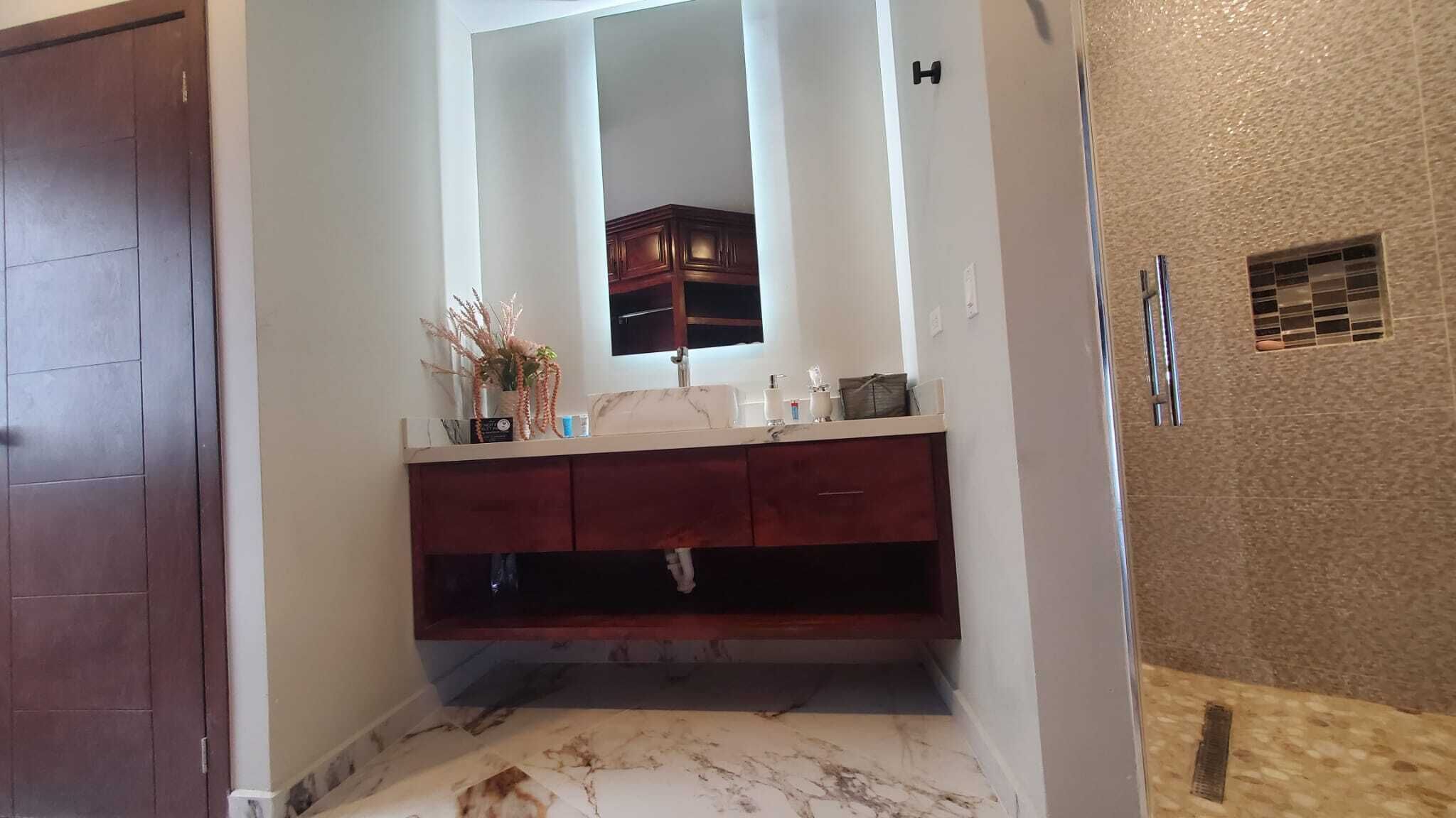 Une salle de bain avec un sol en marbre, un lavabo blanc avec un miroir au-dessus et un meuble en bois en dessous.