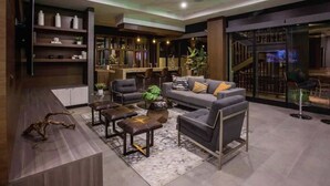 Un moderno espacio de estar con sofá, sillones, una mesa de centro y una estantería.