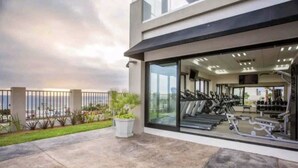 Un gimnasio moderno con equipo de ejercicio, ventanas amplias y vista al mar.