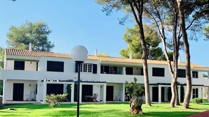 A two-story building with a tiled roof, a lawn, and a pathway.