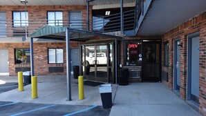 A building with a covered entrance, a parking lot with marked spaces, and a brick facade.
