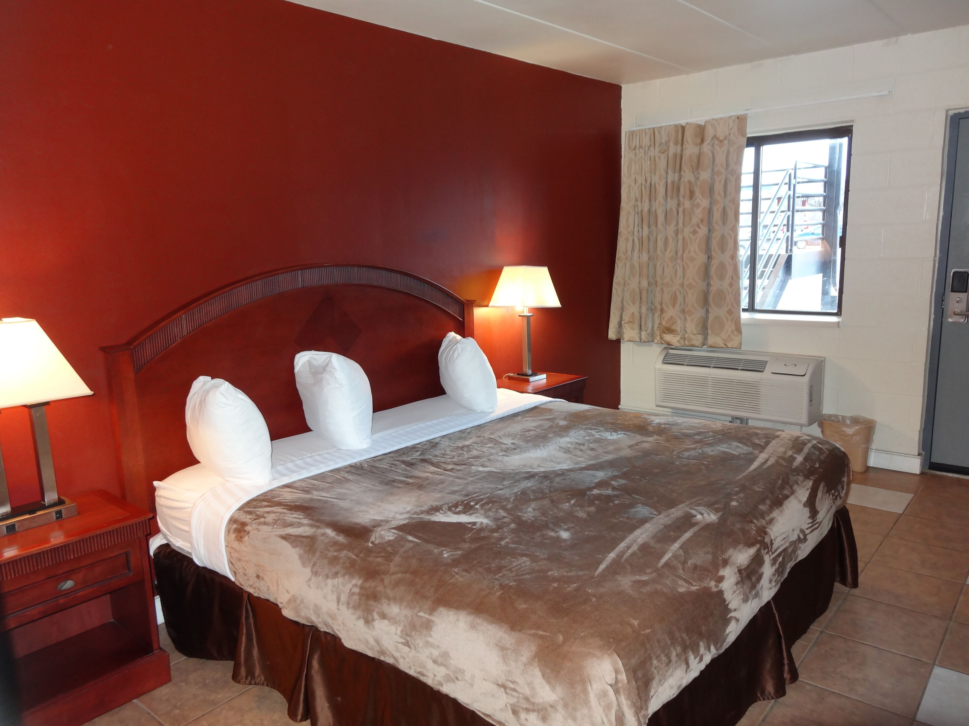Hotelkamer met een groot bed, twee bedlampen, een raam met uitzicht en een airconditioning.