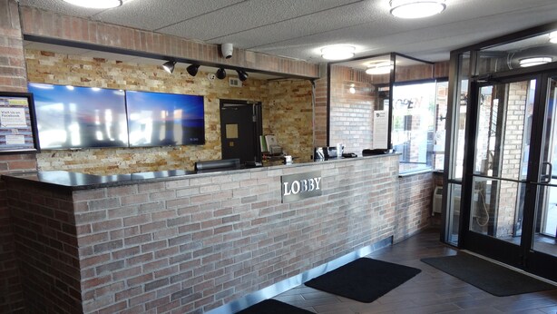 A lobby with a brick reception desk, a large flat-screen TV, and a glass door entrance.