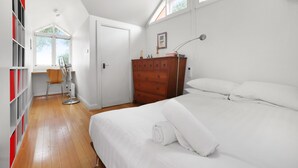 Un dormitorio con una cama grande, un aparador de madera, una silla y un escritorio.