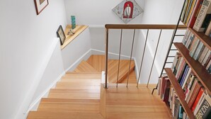 Una escalera con piso de madera que lleva a una zona de entrepiso con tragaluz.