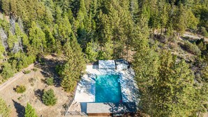An aerial view of a secluded cabin with a swimming pool surrounded by dense forest. - Inn at Sugar Pine Ranch (Groveland)