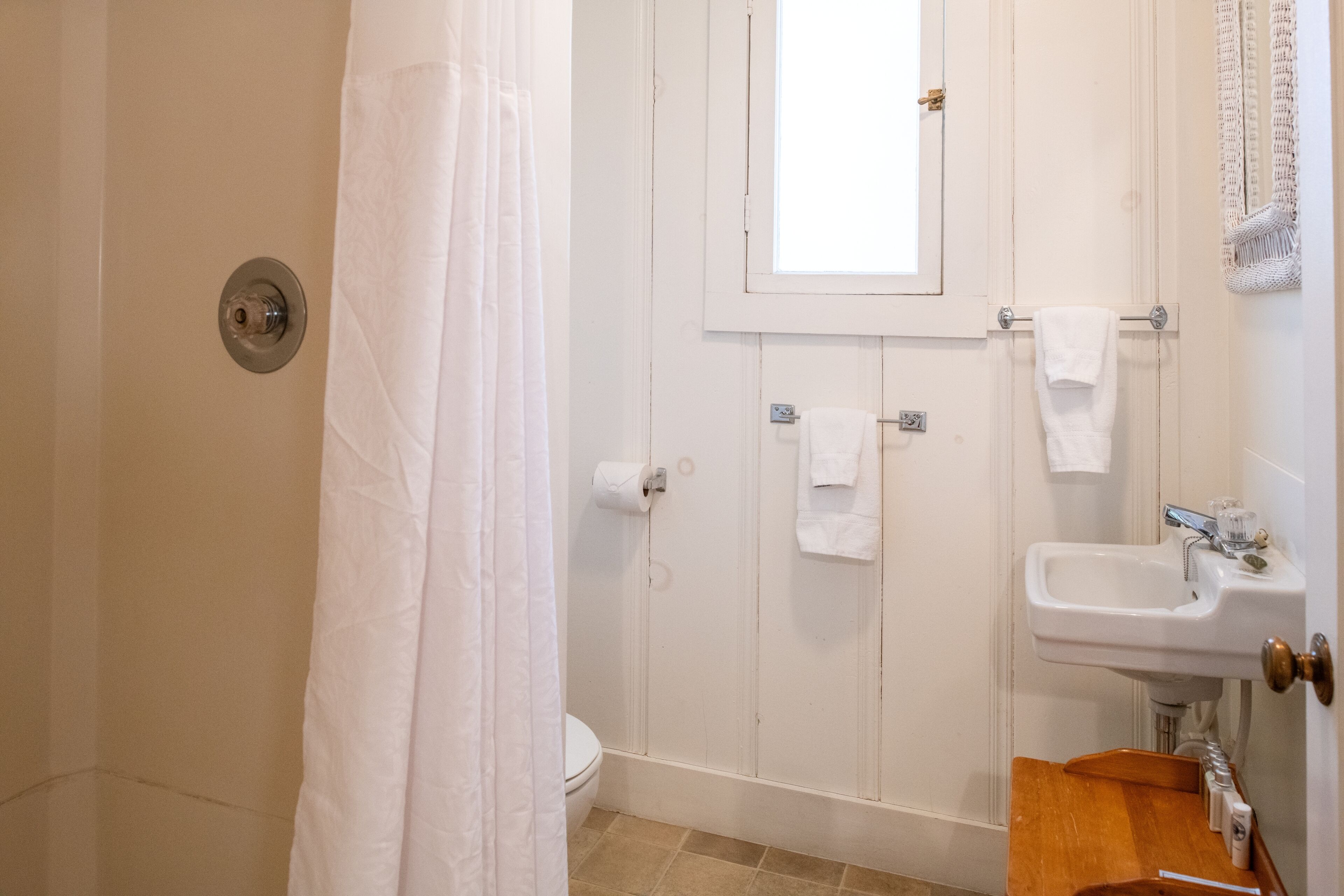 A bathroom with a shower, toilet, sink, and a mirror.