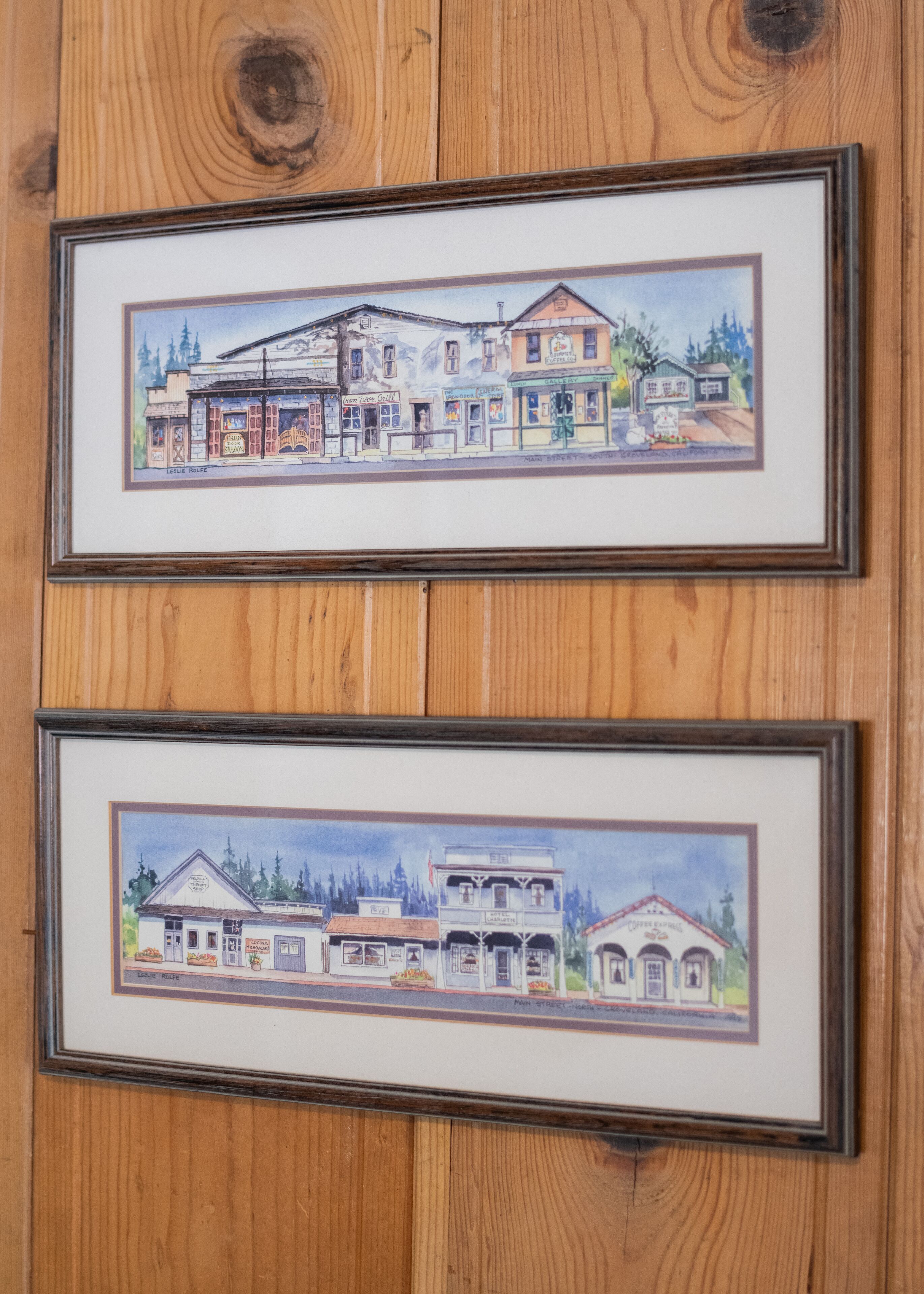 Two framed architectural drawings of buildings with multiple stories, storefronts, and signage.