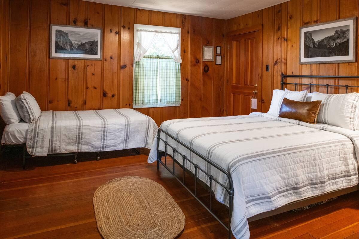 Una habitación con dos camas, paredes de madera y cuadros enmarcados.