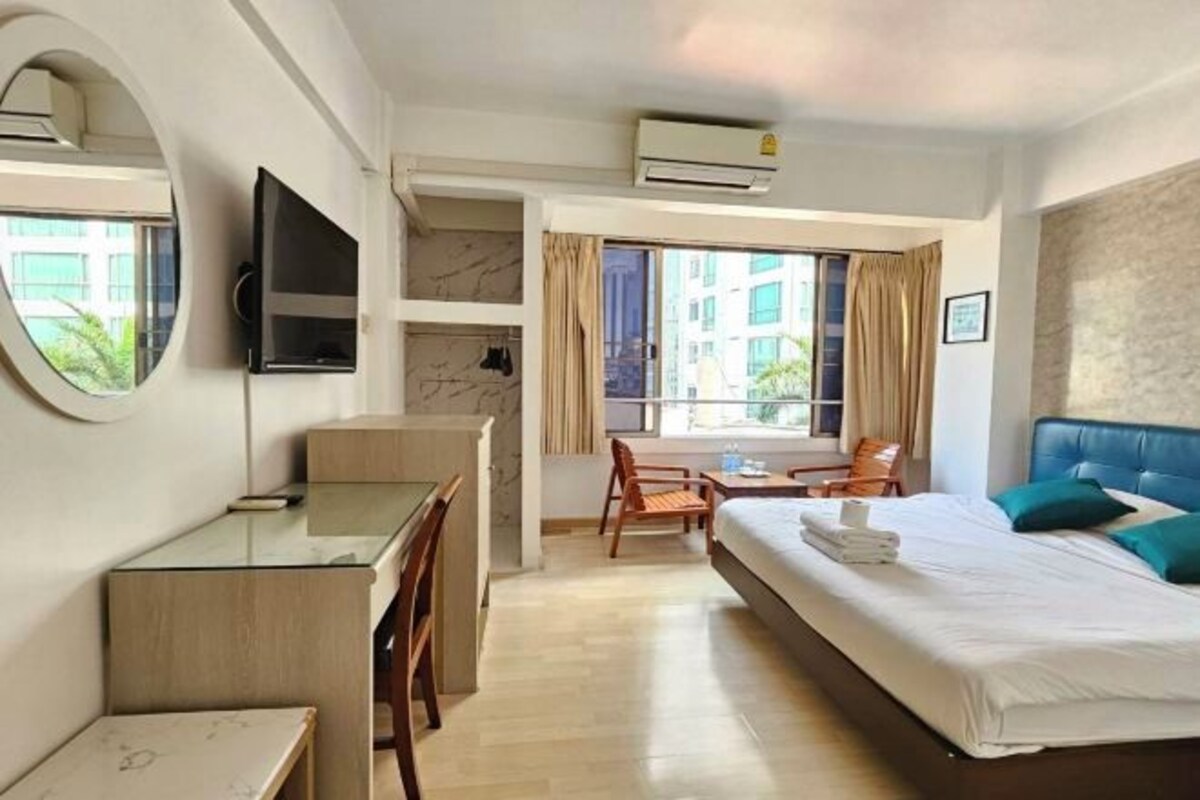 A hotel room with a bed, desk, chair, TV, and a window with curtains.