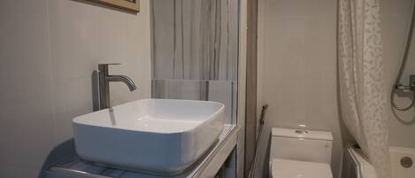 Un baño con lavamanos blanco, inodoro y ducha.